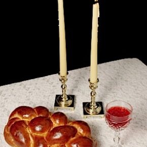 Challah, candlesticks, wine on white tablecloth