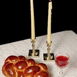 Challah, candlesticks, wine on white tablecloth